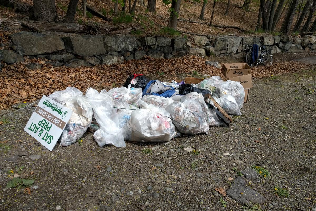 A dozen large bags of trash and some boxes contain trash that has been cleaned up.